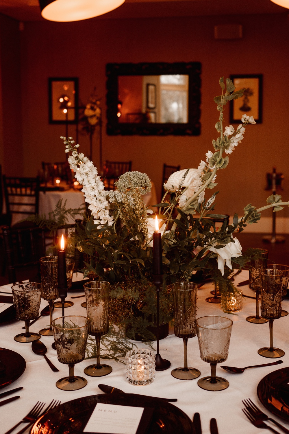 Ambience Venue Styling Cheshire Wedding Decor Breakfast Round Table Black Glassware Cutlery Chairs Candlelight Black Taper Candles High Statement Florals Green White