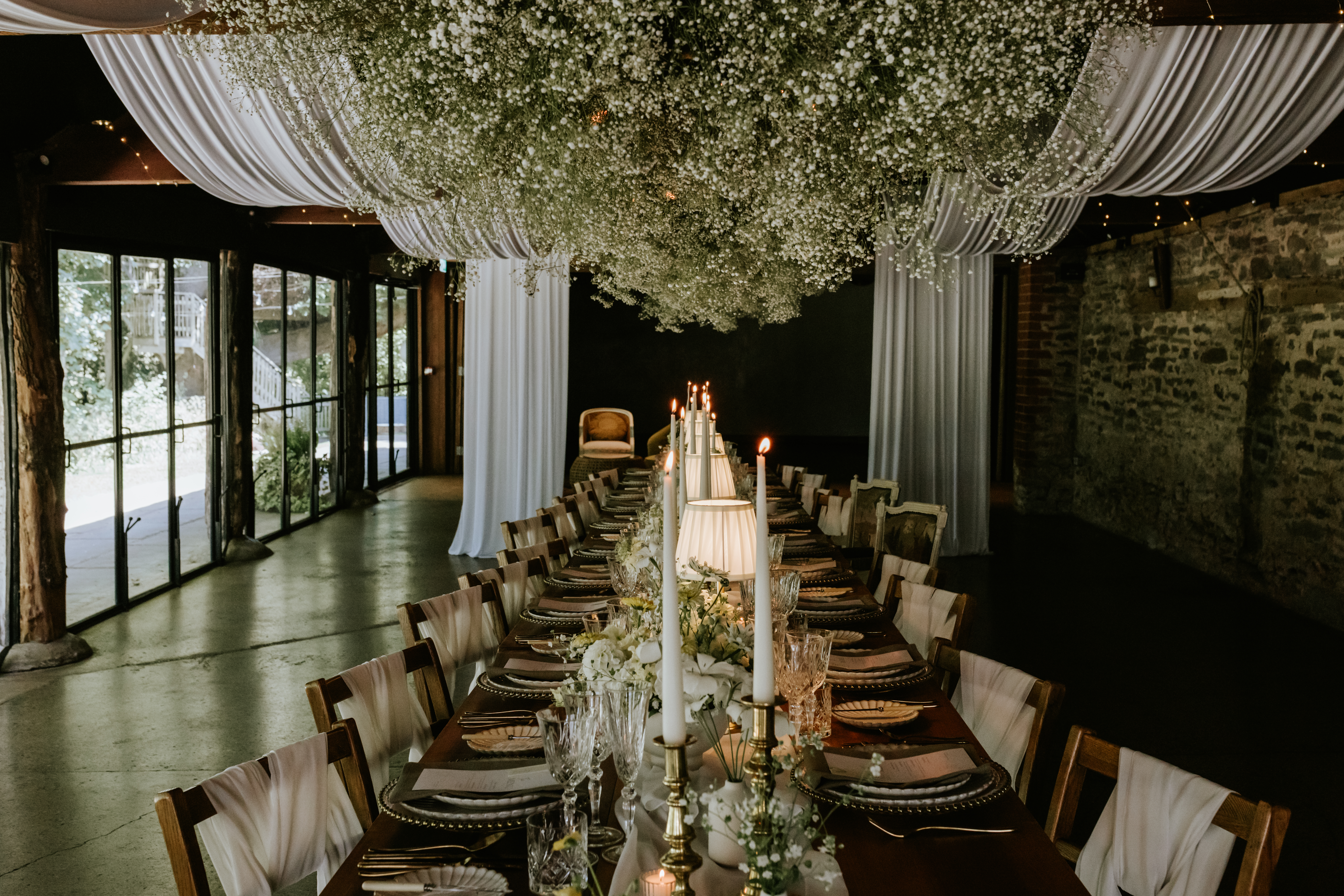 Venue styling banquet dining tables with ceiling drapes and candlelight